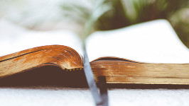 Close up of an open bible on a white surface.